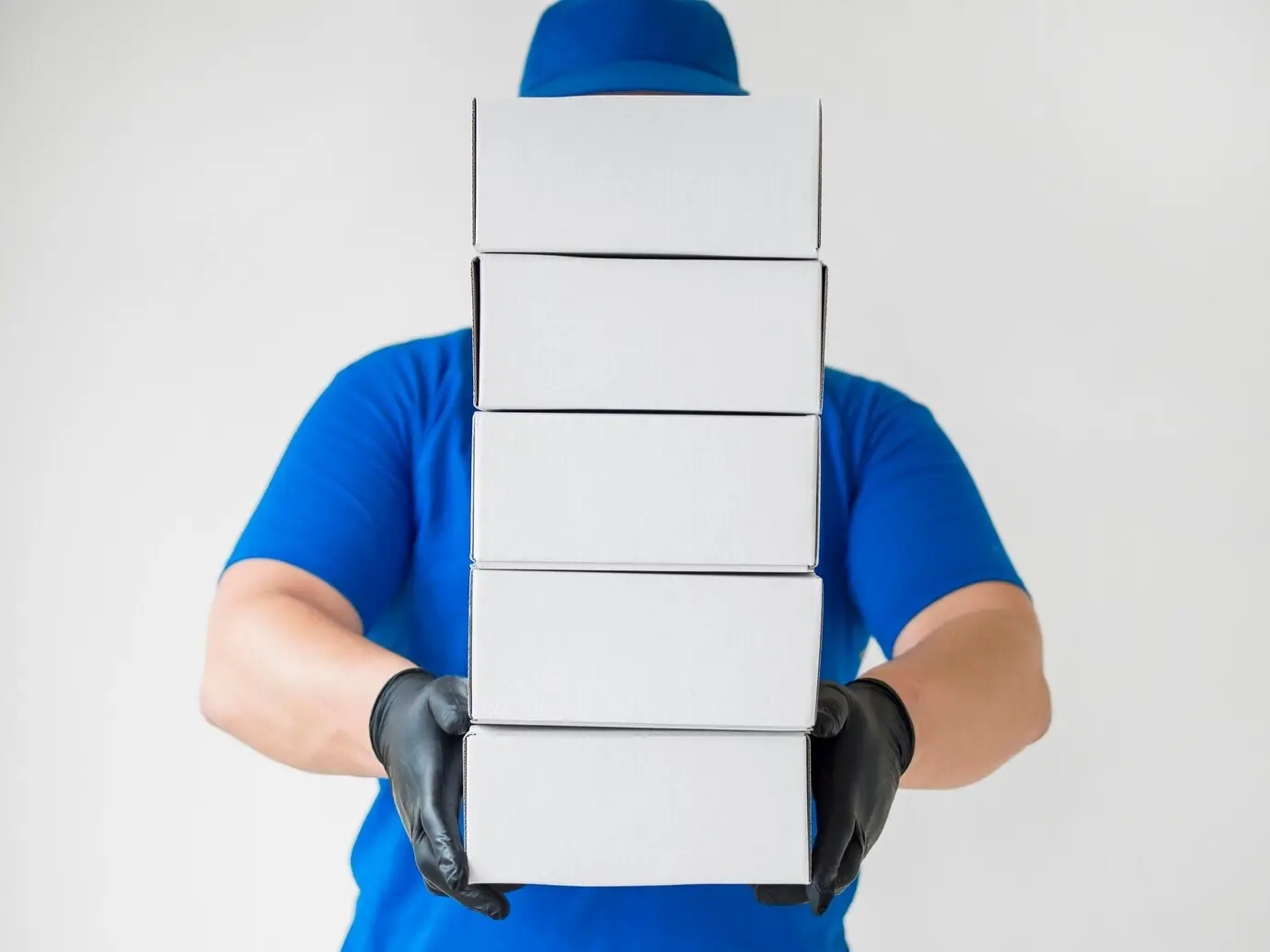 Zusteller mit Handschuhen hält Kartons.