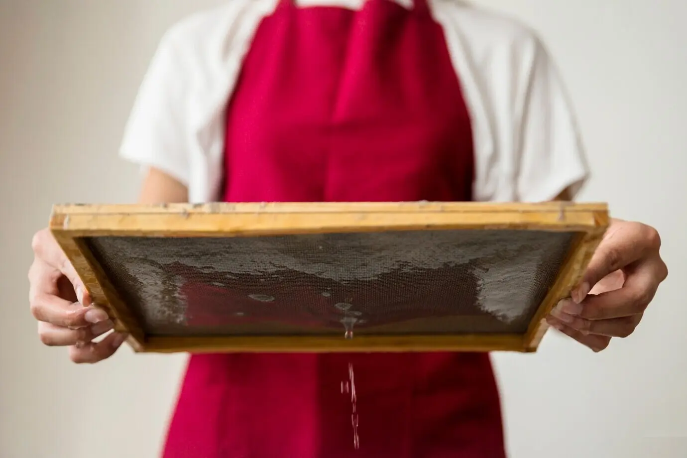 Unterer Bildausschnitt einer Frauenhand, die eine nasse Holzform hält.